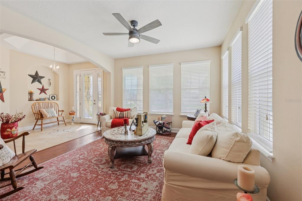 A living room features a white sofa, a round coffee table, and large windows — 4001 CHANDLER ESTATES DRIVE, APOPKA, FL