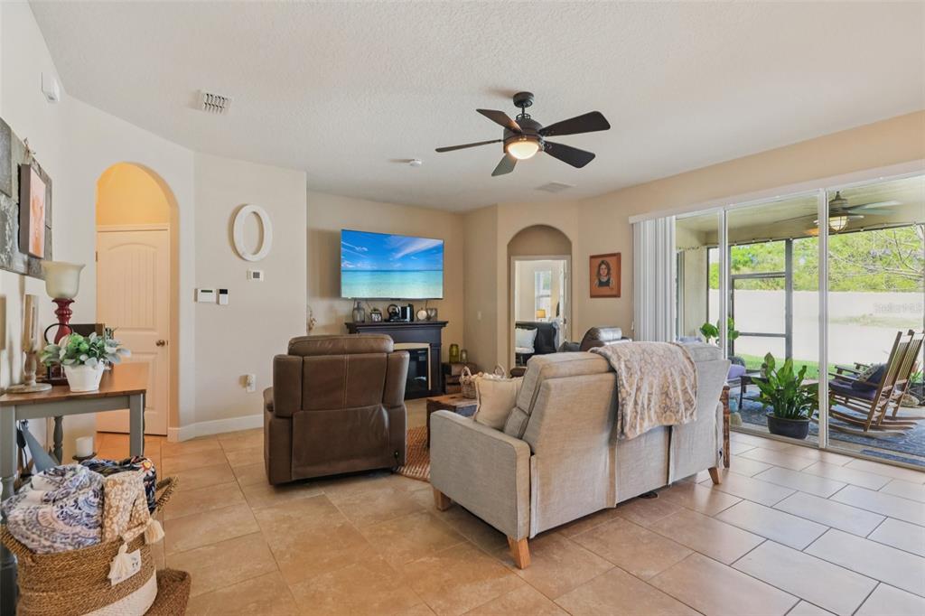 A living room features tile flooring, a ceiling fan, a fireplace, and sliding glass doors — 4001 CHANDLER ESTATES DRIVE, APOPKA, FL