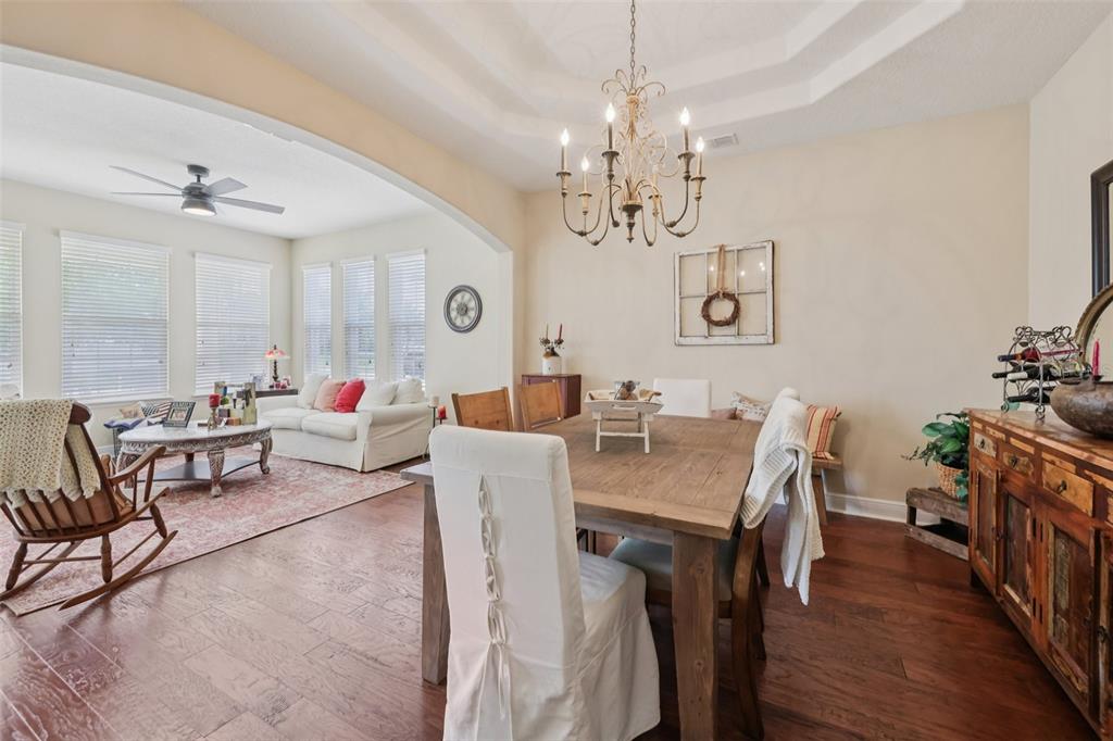 A dining area with a wooden table and chandelier opens into a living room space — 4001 CHANDLER ESTATES DRIVE, APOPKA, FL