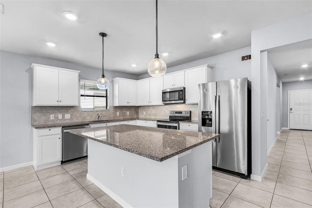 A kitchen features white cabinets, granite countertops, stainless steel appliances, and a central island — 16033 BEACHBERRY DRIVE, NORTH FORT MYERS, FL