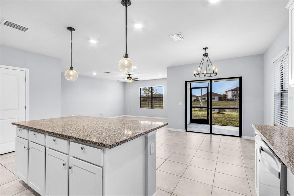 A kitchen island with granite countertops sits in an open-concept room with tile flooring — 16033 BEACHBERRY DRIVE, NORTH FORT MYERS, FL