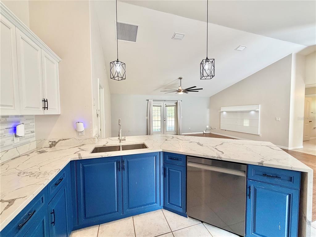 A kitchen with blue lower cabinets, white upper cabinets, and a white marble-look countertop — 12748 NW 148TH TERRACE, ALACHUA, FL