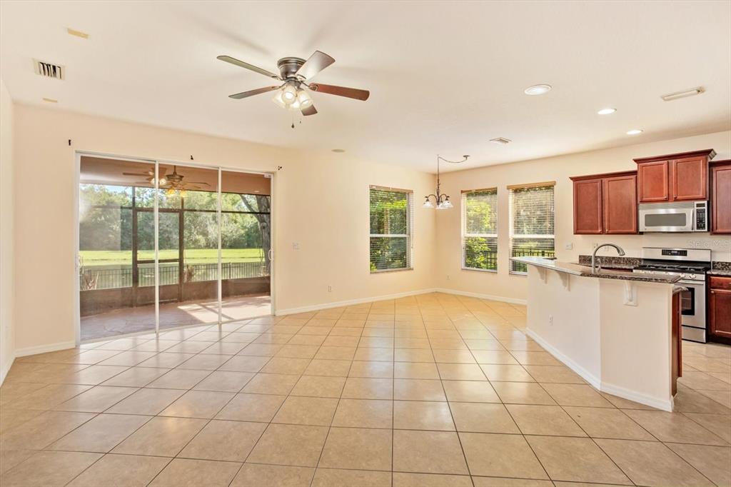 An open-concept kitchen and dining area features tile flooring, dark wood cabinets, and sliding doors — 14543 WHITTRIDGE DRIVE, WINTER GARDEN, FL