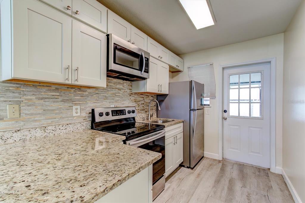 A kitchen features white cabinets, granite countertops, stainless steel appliances, and a glass-paneled door — 232 NORTHSHORE DRIVE UNIT A, ORMOND BEACH, FL