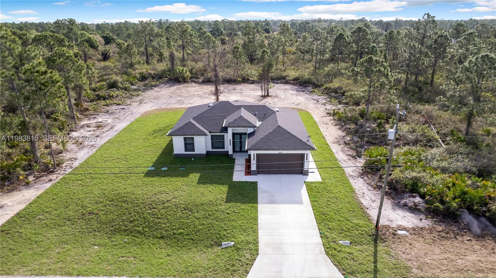 A modern kitchen and dining area feature white cabinetry, marble countertops, and tile flooring — 606 Johns Ave, Lehigh Acres FL 33972, LEHIGH ACRES, FL
