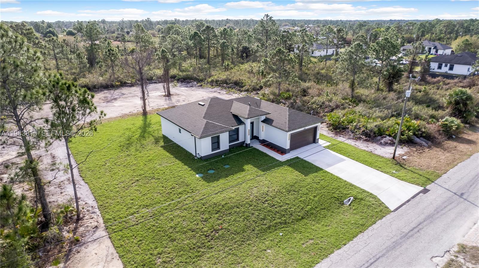 A modern open-concept kitchen and dining area features white cabinetry, marble-topped surfaces, and tile flooring — 606 Johns Ave, Lehigh Acres FL 33972, LEHIGH ACRES, FL