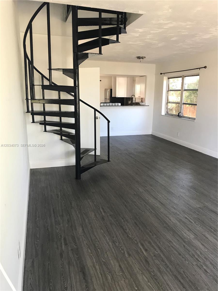 A living room features dark wood-look flooring, white walls, and a black metal spiral staircase — 2444 SW 58 Mnr, Dania Beach FL 33312, DANIA BEACH, FL