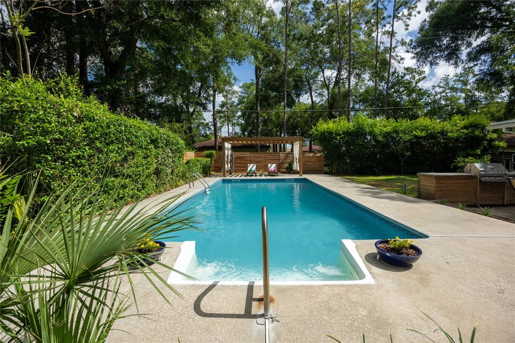 A rectangular swimming pool with a shallow entry step sits in a fenced backyard — 4204 NW 19TH PLACE, GAINESVILLE, FL