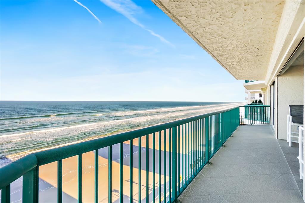 A high-rise balcony with a teal railing overlooks a sandy beach and the ocean — 2055 S ATLANTIC AVENUE UNIT 1006, DAYTONA BEACH, FL