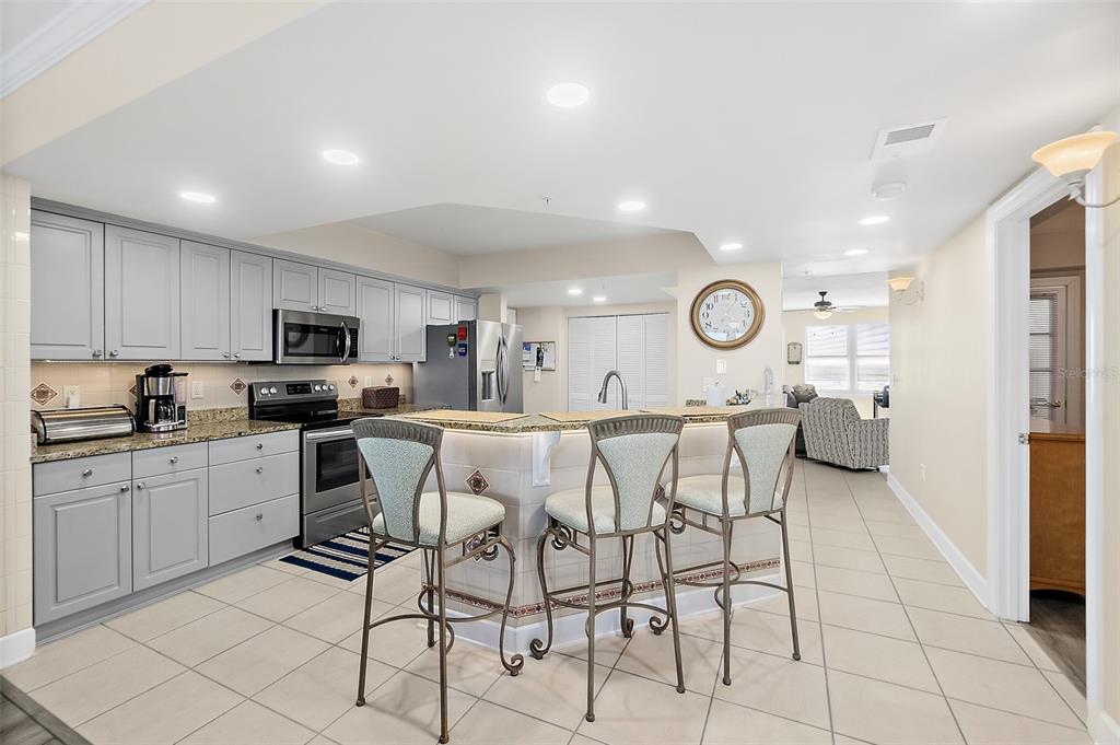 A kitchen features gray cabinets, granite countertops, stainless steel appliances, and a breakfast bar — 2055 S ATLANTIC AVENUE UNIT 1006, DAYTONA BEACH, FL