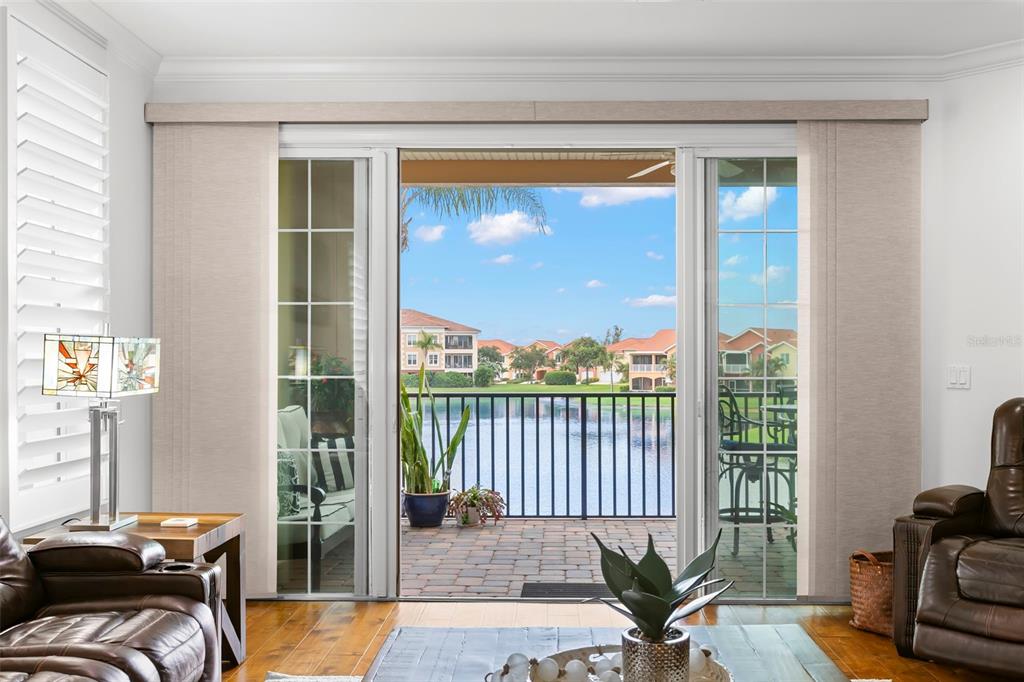 A living room with sliding glass doors opening to a balcony overlooking a lake — 6 ACADEMY WAY S UNIT 221, ST PETERSBURG, FL