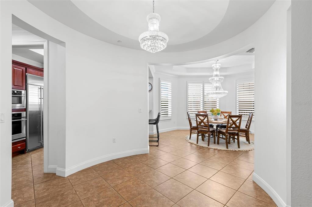A dining area with a crystal chandelier and tile flooring connects to a kitchen — 6 ACADEMY WAY S UNIT 221, ST PETERSBURG, FL