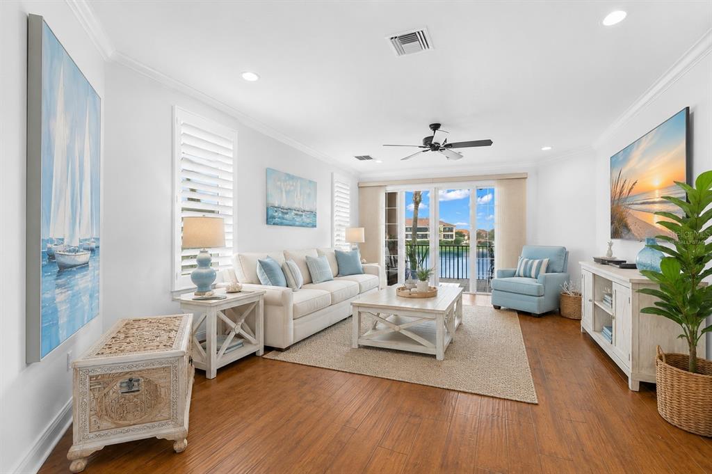 A bright living room features a white sofa, coffee table, and a view of water — 6 ACADEMY WAY S UNIT 221, ST PETERSBURG, FL