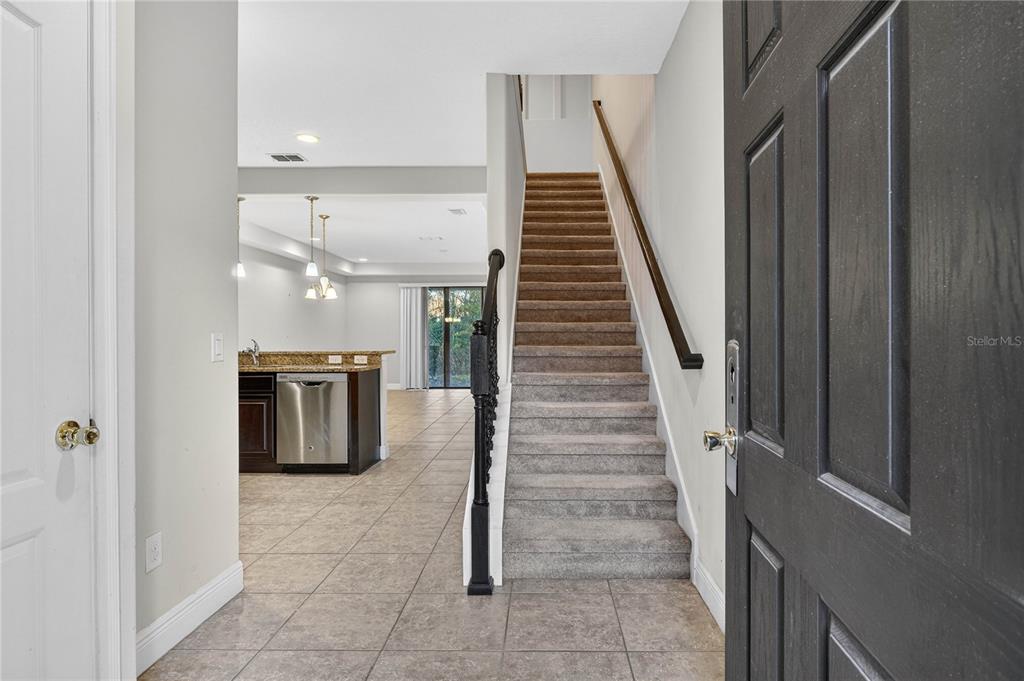 An entryway features a carpeted staircase, tile flooring, and a view into the kitchen area — 8087 BROOKSVILLE DRIVE, DAVENPORT, FL