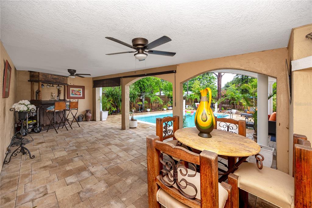 A covered patio features a bar, dining set, and views of an outdoor swimming pool — 755 43RD STREET N, ST PETERSBURG, FL