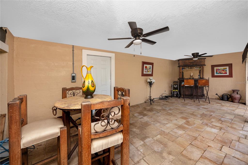 A covered patio features a small wooden dining set, a bar area, and tiled flooring — 755 43RD STREET N, ST PETERSBURG, FL