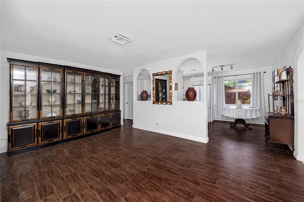 A dining room features dark wood-look tile floors, a large display cabinet, and arched openings — 755 43RD STREET N, ST PETERSBURG, FL