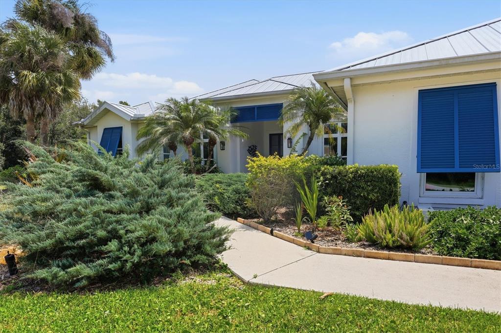 The front entrance of a house features a glass door, palm trees, and landscaping — 4575 SATINLEAF LANE, SARASOTA, FL