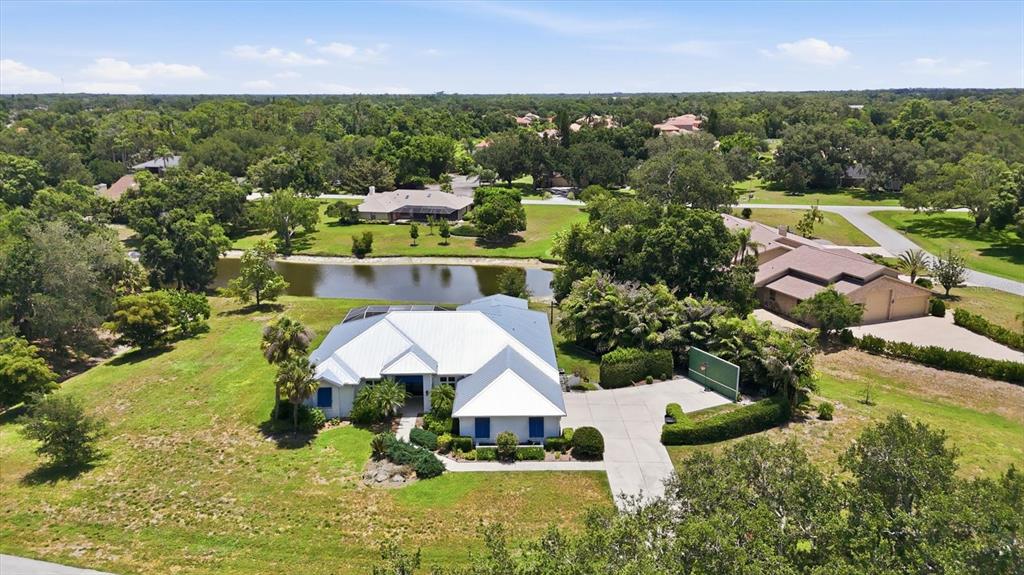 A white house with a metal roof and a three-car garage faces a concrete driveway — 4575 SATINLEAF LANE, SARASOTA, FL