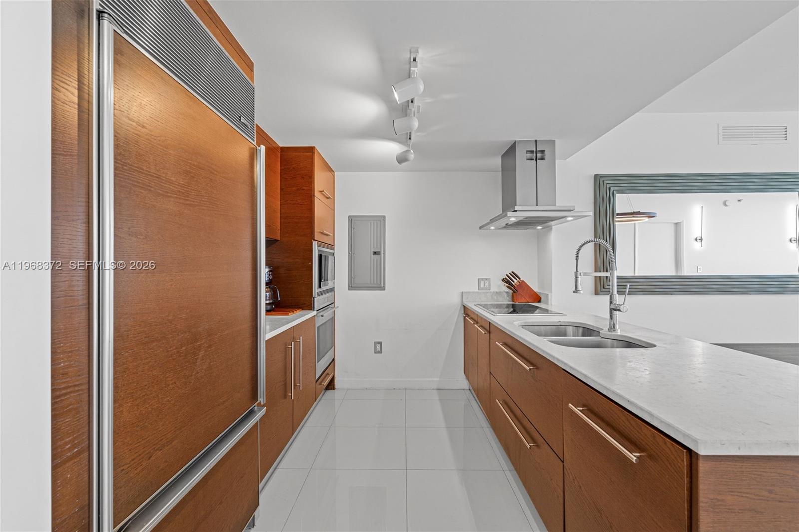 A modern kitchen features wood cabinets, white countertops, a double sink, and white tile flooring — 495 Brickell Ave # 905, Miami FL 33131, MIAMI, FL