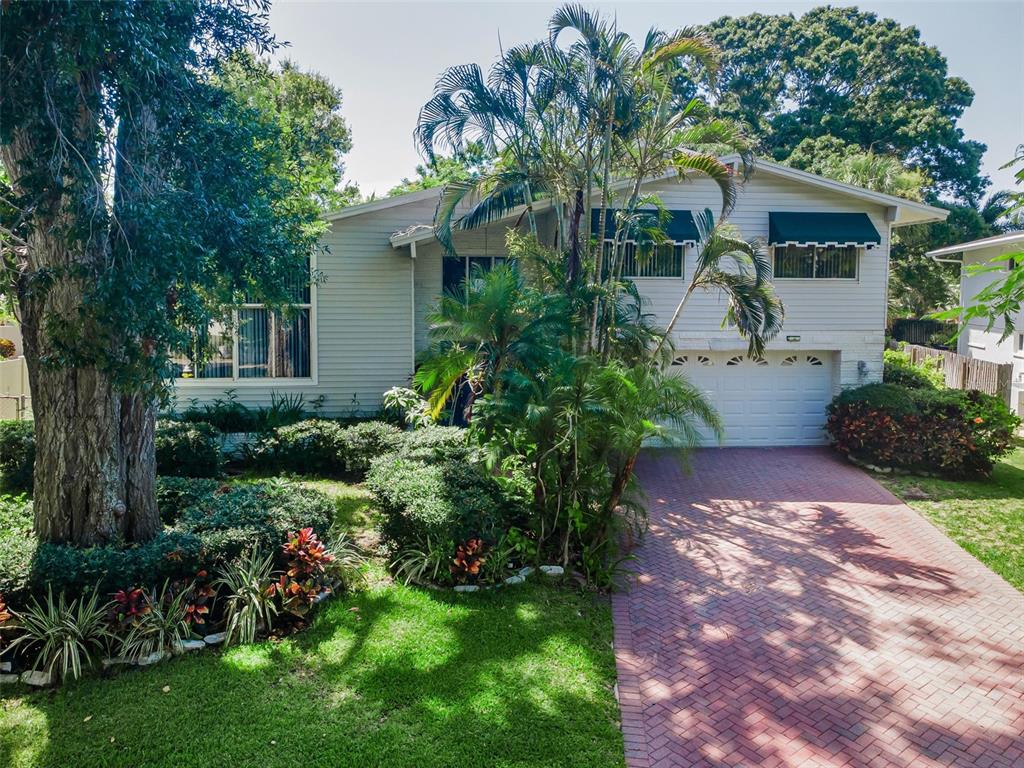 A two-story house with light siding, a brick driveway, and lush landscaping — 14279 85TH AVENUE, SEMINOLE, FL