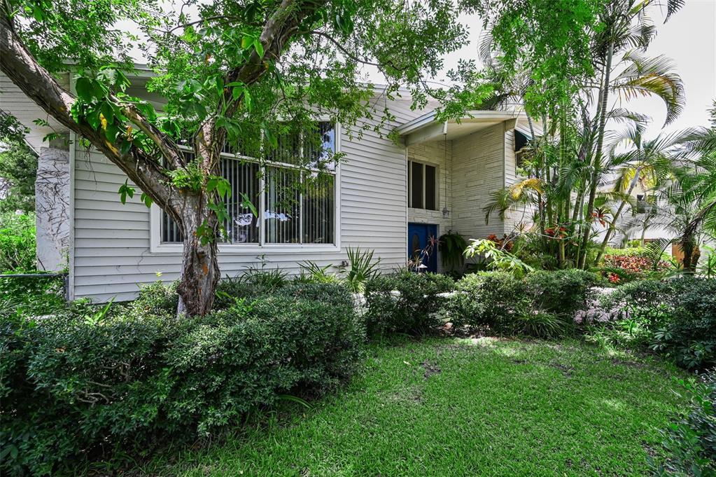 A single-story house with light-colored siding, a large front window, and lush landscaping — 14279 85TH AVENUE, SEMINOLE, FL