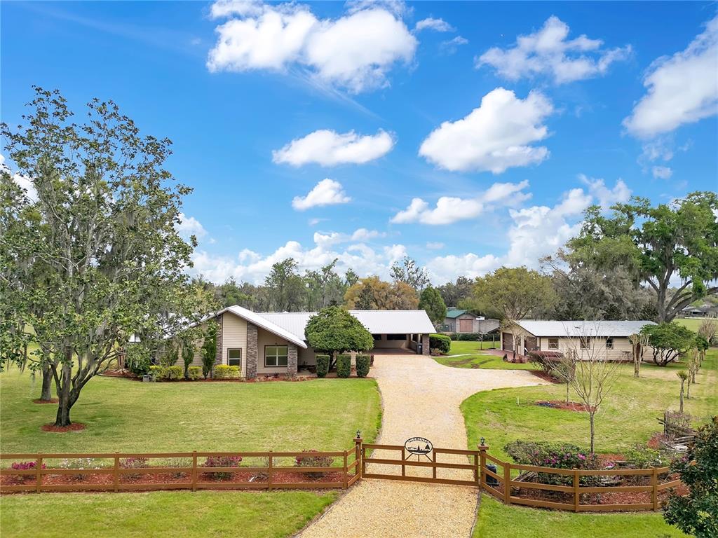 A gravel driveway leads through a wooden gate to a house with a metal roof — 1401 BUELL COURT, PLANT CITY, FL