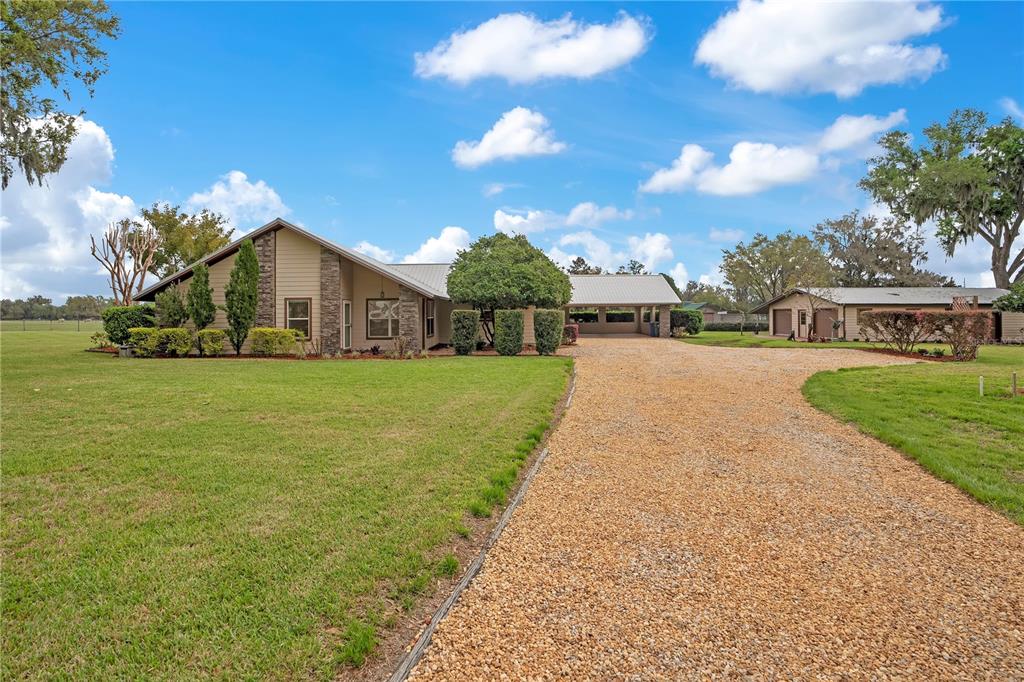A single-story house with a gravel driveway, stone accents, and a large grassy yard — 1401 BUELL COURT, PLANT CITY, FL