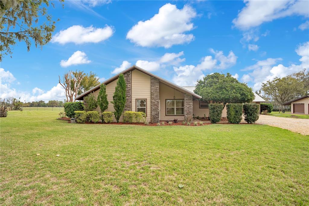 A single-story house with stone accents and tan siding sits on a large grassy lot — 1401 BUELL COURT, PLANT CITY, FL