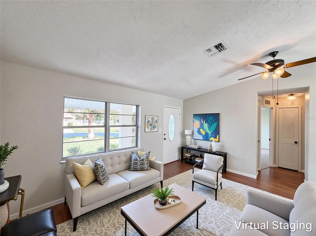 A living room with a sofa, armchairs, coffee table, and wood-look flooring — 5304 HARBINGER ROAD, SPRING HILL, FL
