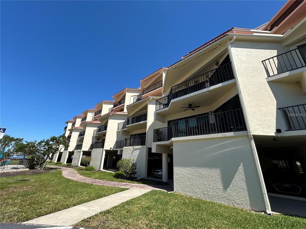 A multi-story apartment building exterior with balconies and ground-level covered parking — 204 3RD STREET W UNIT 405, BRADENTON, FL