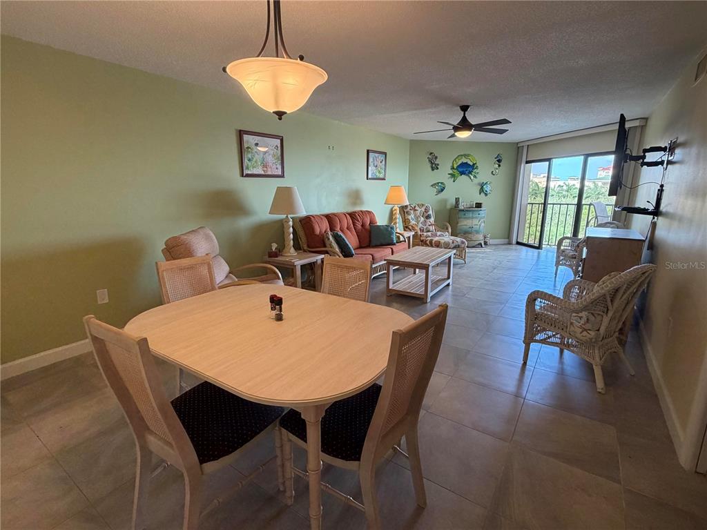 A dining area and living room feature tile floors, a ceiling fan, and balcony access — 204 3RD STREET W UNIT 405, BRADENTON, FL