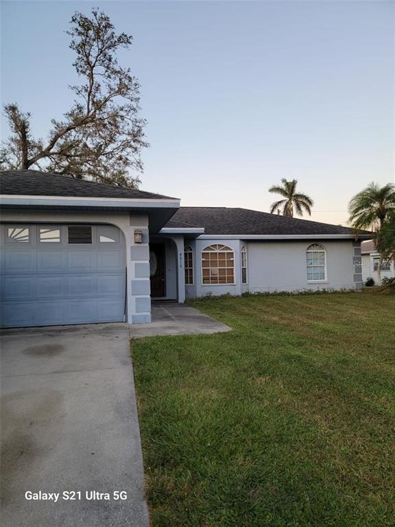 A single-story house with a light blue exterior, a garage, and a front lawn — 4016 BULA LANE, NORTH PORT, FL