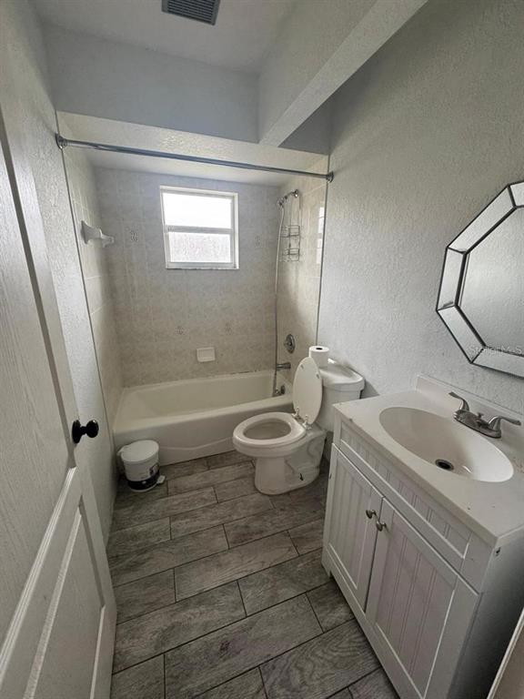 A bathroom features a white vanity, a toilet, and a bathtub with a shower curtain rod — 4016 BULA LANE, NORTH PORT, FL