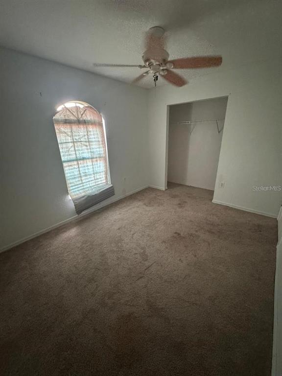 An empty bedroom features beige carpeting, white walls, a ceiling fan, and an arched window — 4016 BULA LANE, NORTH PORT, FL
