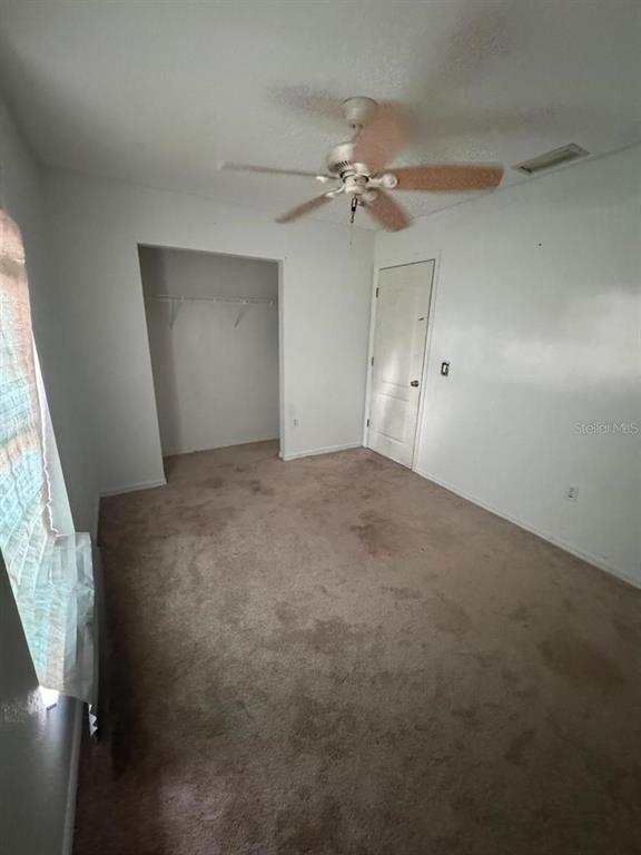 A bedroom with beige carpet, a ceiling fan, a closet, and a white door — 4016 BULA LANE, NORTH PORT, FL
