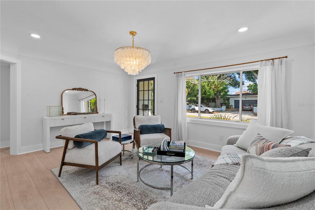 A living room features light wood floors, a chandelier, two armchairs, and a sofa — 1211 16TH AVENUE N, ST PETERSBURG, FL