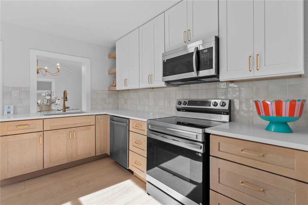 A kitchen features light wood lower cabinets, white upper cabinets, and a stainless steel stove — 1211 16TH AVENUE N, ST PETERSBURG, FL