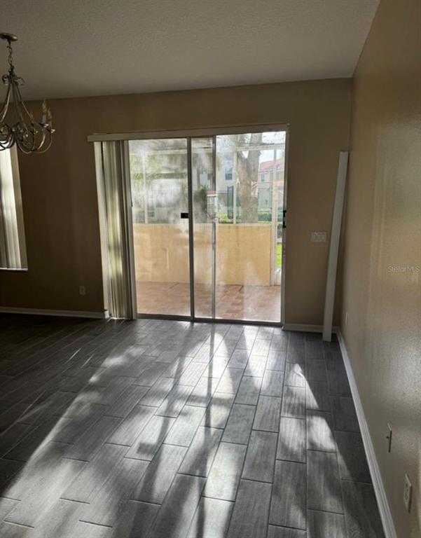 A room with gray wood-look tile flooring and a sliding glass door leading to a patio — 1289 S BEACH CIRCLE, KISSIMMEE, FL