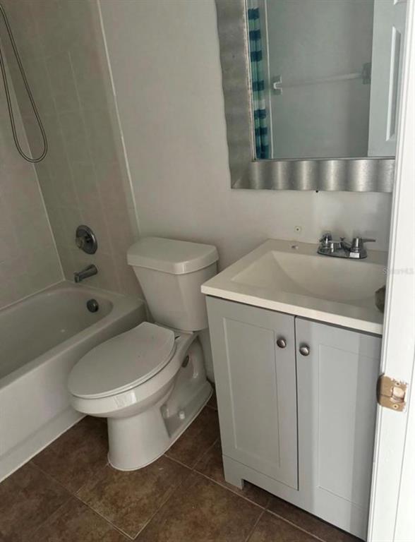 A bathroom features a white toilet, a grey vanity with a sink, and a bathtub — 1289 S BEACH CIRCLE, KISSIMMEE, FL