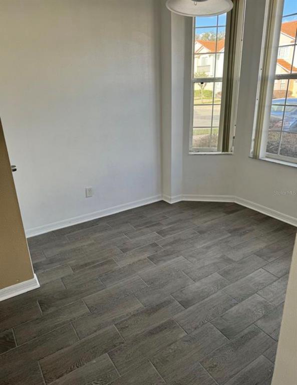 An empty room with gray wood-look tile flooring and a bay window — 1289 S BEACH CIRCLE, KISSIMMEE, FL
