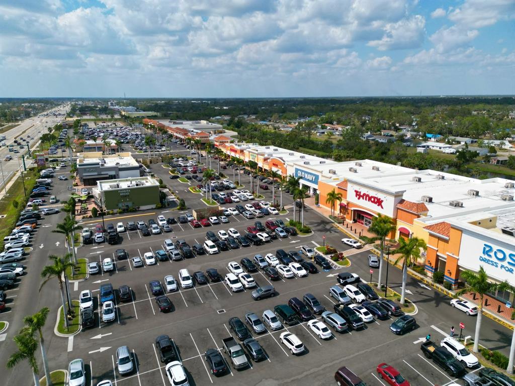 An aerial view shows a large shopping center parking lot with several retail stores — GILBERT STREET, NORTH PORT, FL