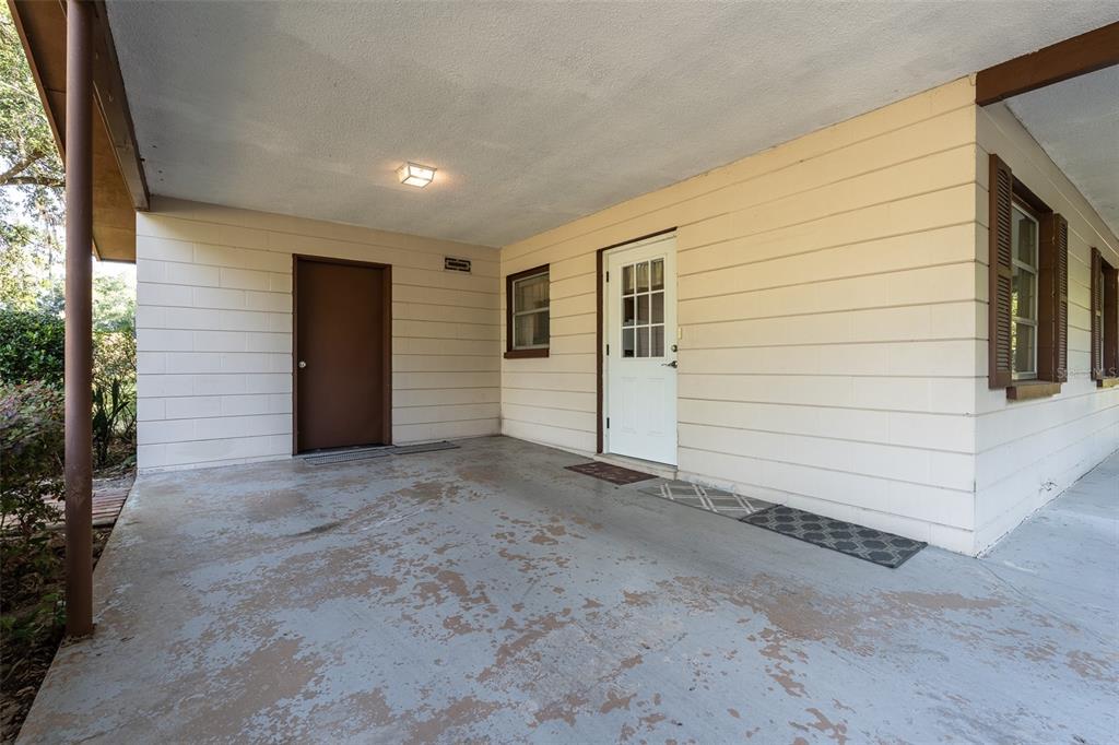A covered concrete patio features a brown storage door and a white entry door — 2217 NW 52 STREET, OCALA, FL