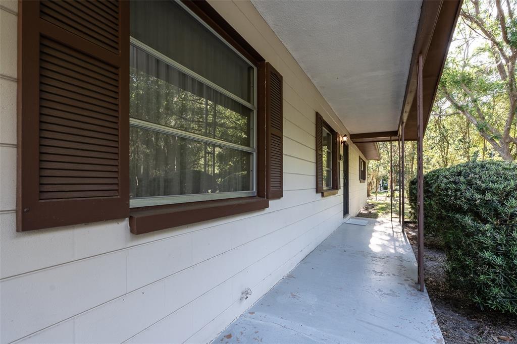 A view of a covered concrete porch along the side of a beige house — 2217 NW 52 STREET, OCALA, FL