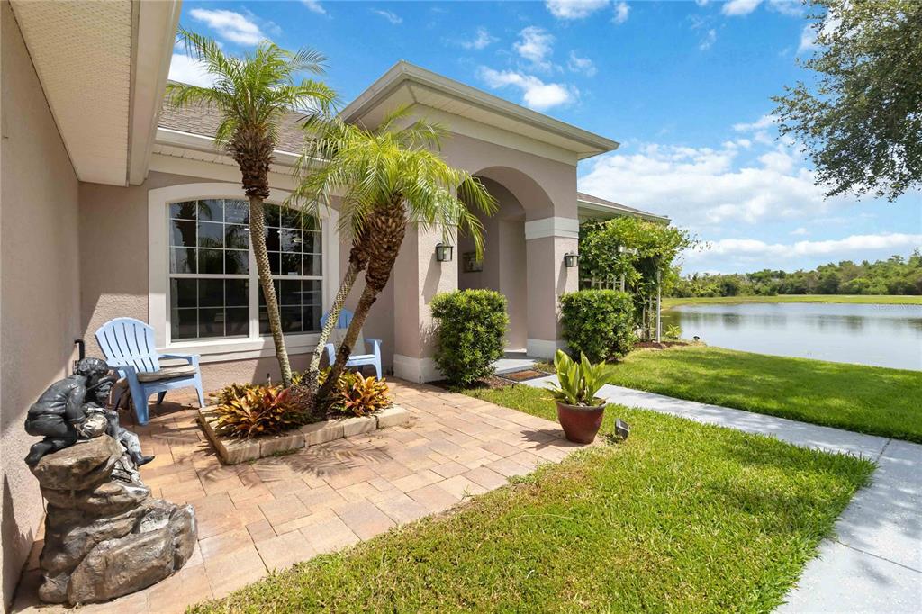 A paved patio with palm trees and a statue overlooks a lake beside a house — 3014 SAND STONE CIRCLE, ST CLOUD, FL