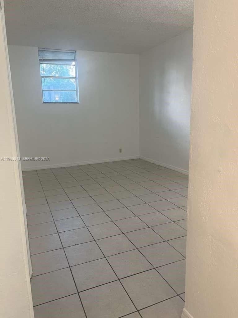 An empty room features white walls, a single window, and light-colored tile flooring — 4550 NW 9th St # 114E, Miami FL 33126, MIAMI, FL
