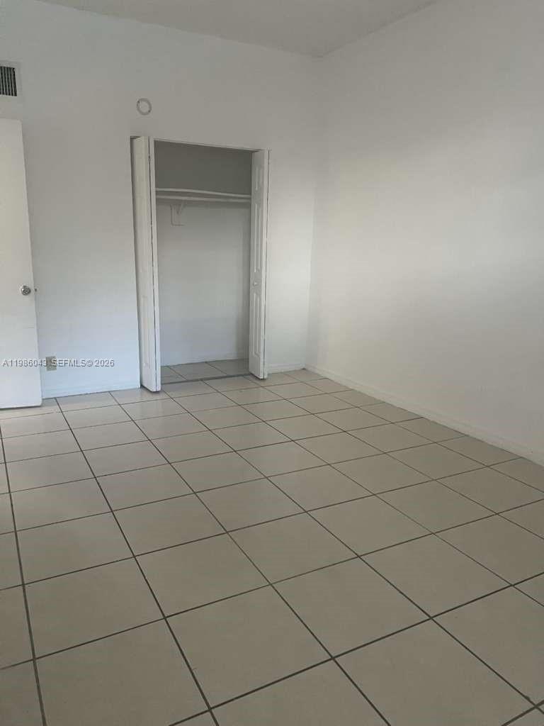 An empty room features light-colored floor tiles, white walls, and an open closet — 4550 NW 9th St # 114E, Miami FL 33126, MIAMI, FL