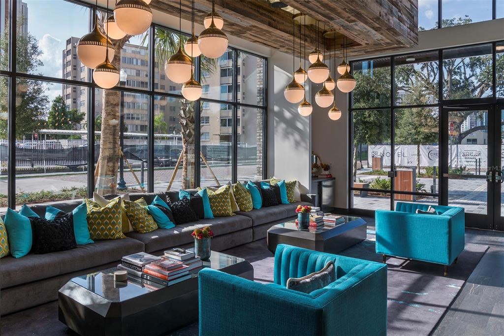 A modern lounge features a long gray sofa, teal armchairs, glass coffee tables, and globe pendant lights — 733 MAIN LANE UNIT 2, ORLANDO, FL