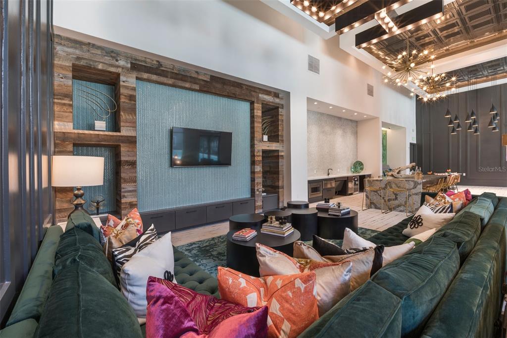 A modern living room features a green velvet sectional, a tiled accent wall, and chandeliers — 733 MAIN LANE UNIT 2, ORLANDO, FL