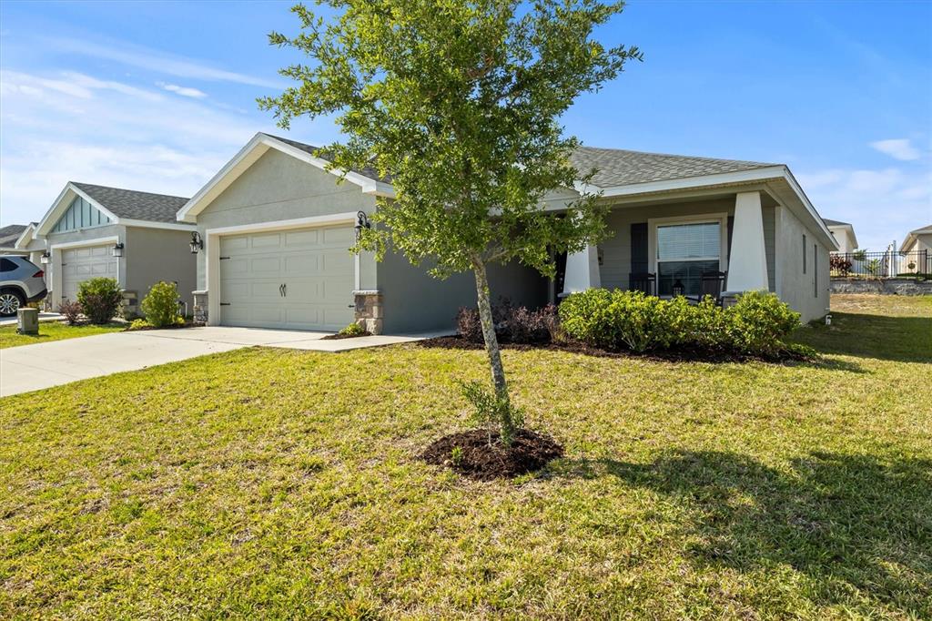 A single-story suburban house with a two-car garage, a front lawn, and a young tree — 2008 NOBLE DRIVE, DAVENPORT, FL